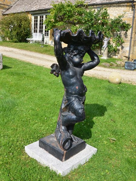 A large cast iron figure holding aloft a conch shell by the Durenne Foundry